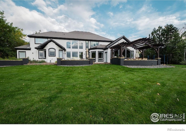 back of house featuring stucco siding, a yard, and a pergola