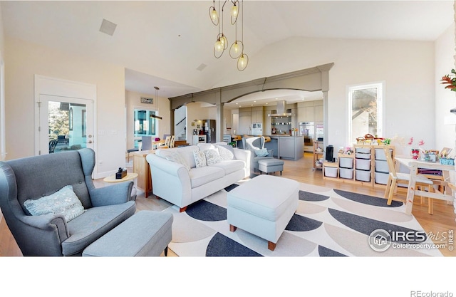 living room featuring high vaulted ceiling, light wood-style flooring, and a chandelier