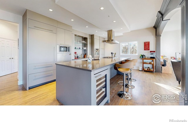 10667 E Goose Haven Dr, Lafayette, CO 80026 - kitchen with island range hood, beverage cooler, light wood-type flooring, a sink, and a center island with sink