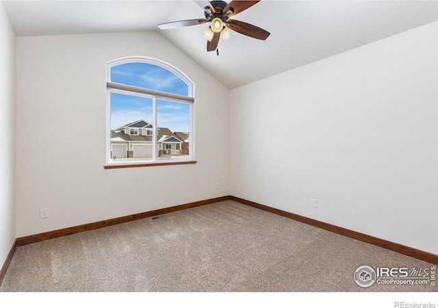 carpeted empty room with baseboards, vaulted ceiling, and a ceiling fan