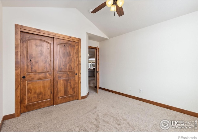 unfurnished bedroom featuring a ceiling fan, lofted ceiling, light colored carpet, and baseboards