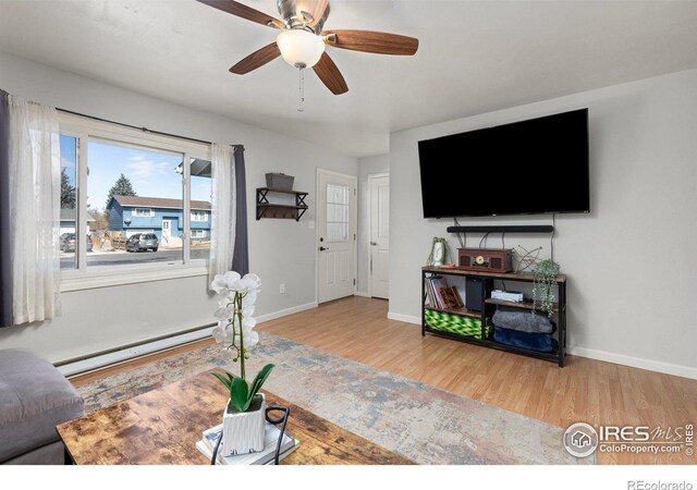 living area featuring light wood finished floors, baseboards, and a baseboard heating unit