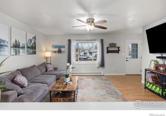 living room featuring a ceiling fan, light wood-type flooring, baseboards, and a baseboard radiator