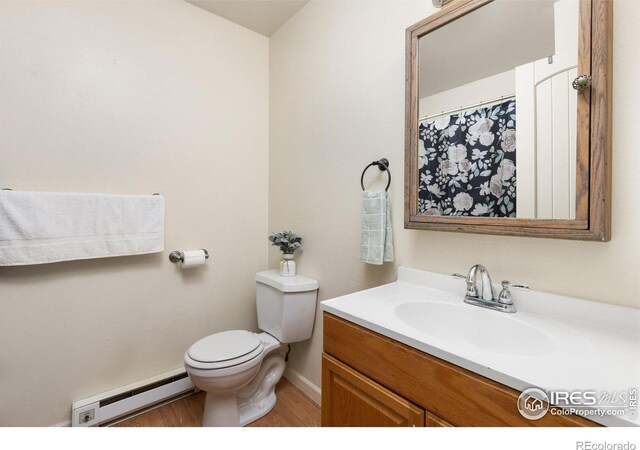 bathroom with toilet, wood finished floors, vanity, baseboards, and baseboard heating