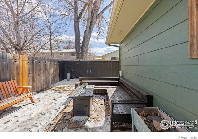 snow covered patio with a fenced backyard