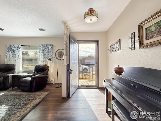 entryway with dark wood-style floors, a wealth of natural light, a textured ceiling, and visible vents