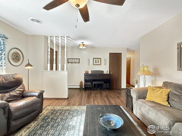 living area featuring dark wood finished floors, visible vents, baseboard heating, a ceiling fan, and a textured ceiling