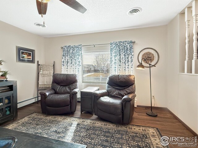 sitting room featuring dark wood-type flooring, baseboard heating, and visible vents