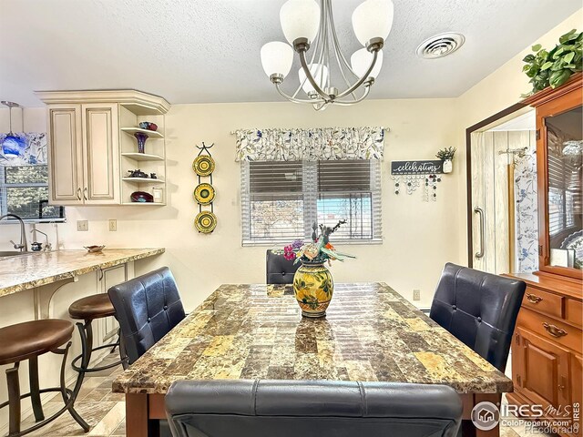 dining area featuring a textured ceiling, visible vents, and an inviting chandelier