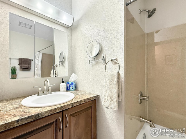 bathroom featuring a textured wall, vanity, and shower / bathing tub combination