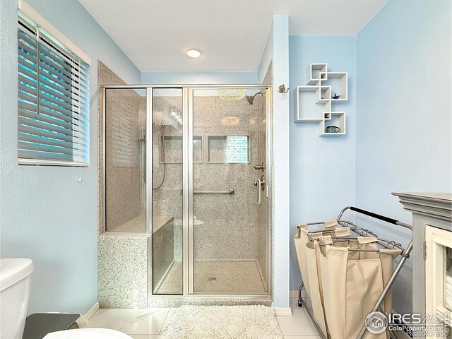 bathroom with a wealth of natural light, a shower stall, and toilet