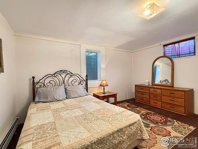 bedroom featuring a baseboard heating unit and a textured ceiling