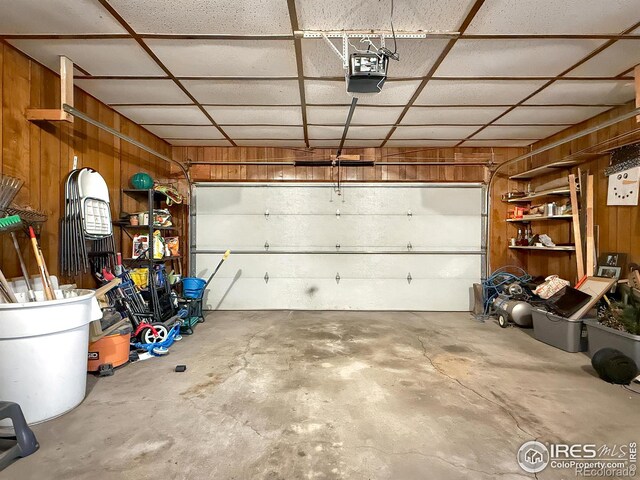 garage with a garage door opener and wood walls