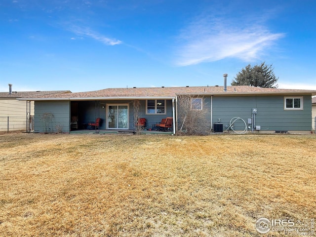 back of property with a yard, cooling unit, and fence