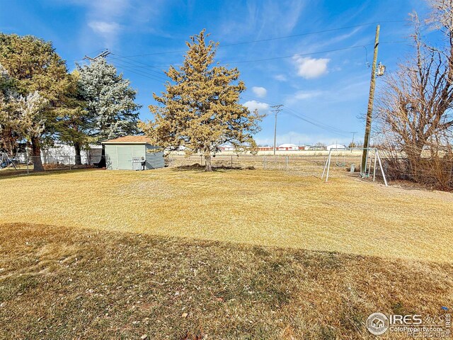 view of yard featuring a shed, fence, and an outdoor structure