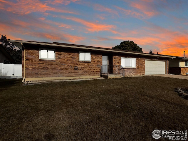 single story home featuring a garage, a yard, driveway, and brick siding