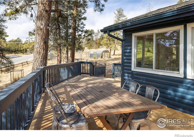 wooden deck featuring an outbuilding, a storage shed, and outdoor dining area