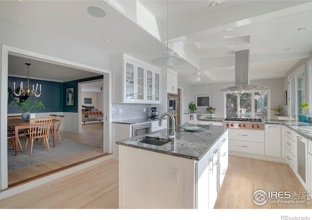 7034 Indian Peaks Trl, Boulder, CO 80301 - kitchen with a sink, stainless steel gas stovetop, light wood-style floors, island exhaust hood, and glass insert cabinets