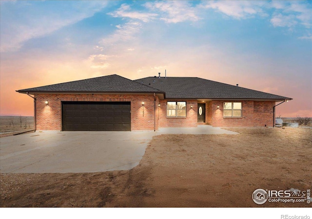 view of front of home featuring driveway, an attached garage, and brick siding