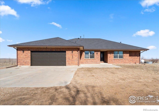 single story home with a garage, brick siding, driveway, and a shingled roof