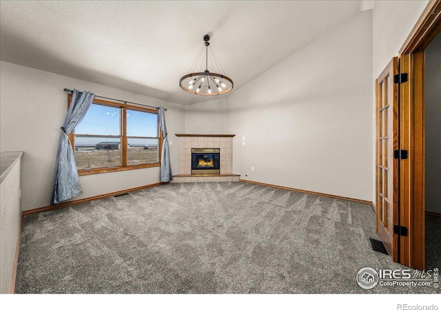 11837 County Road 39, Fort Lupton, CO 80621 - unfurnished living room featuring baseboards, an inviting chandelier, a tiled fireplace, vaulted ceiling, and carpet flooring