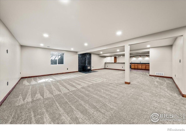 11837 County Road 39, Fort Lupton, CO 80621 - below grade area featuring visible vents, a wood stove, carpet floors, and baseboards