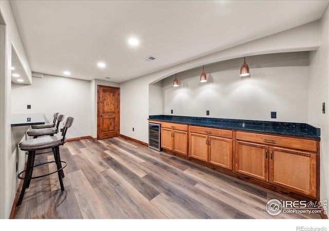 11837 County Road 39, Fort Lupton, CO 80621 - kitchen with visible vents, dark countertops, brown cabinetry, wood finished floors, and beverage cooler