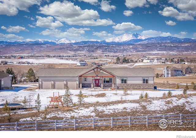 view of front of property with stone siding, fence, and a mountain view