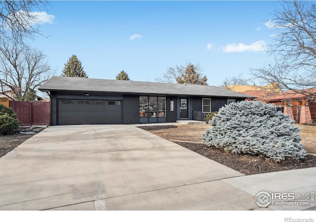 view of front of home featuring an attached garage, driveway, fence, and brick siding