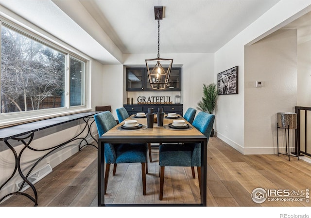 dining room with wood-type flooring, visible vents, and baseboards