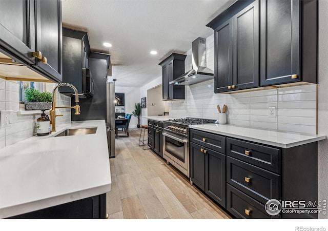 kitchen featuring tasteful backsplash, stainless steel range, light countertops, light wood-type flooring, and wall chimney range hood