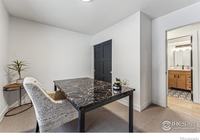 home office with baseboards, a sink, and light colored carpet