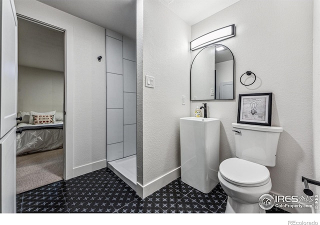 ensuite bathroom with a textured wall, toilet, ensuite bath, a walk in shower, and baseboards