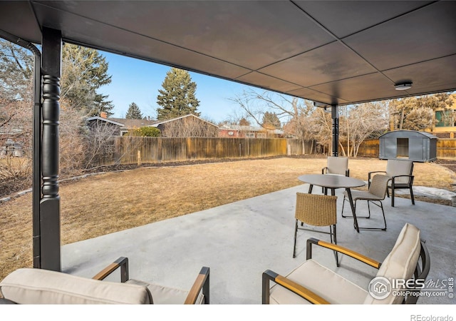 view of patio with a fenced backyard, a storage unit, outdoor dining area, an outdoor structure, and an outdoor living space