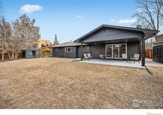 rear view of property featuring an outbuilding, a fenced backyard, a storage unit, board and batten siding, and a patio area