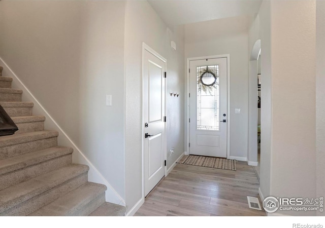 entrance foyer featuring light wood-style flooring, stairs, visible vents, and baseboards