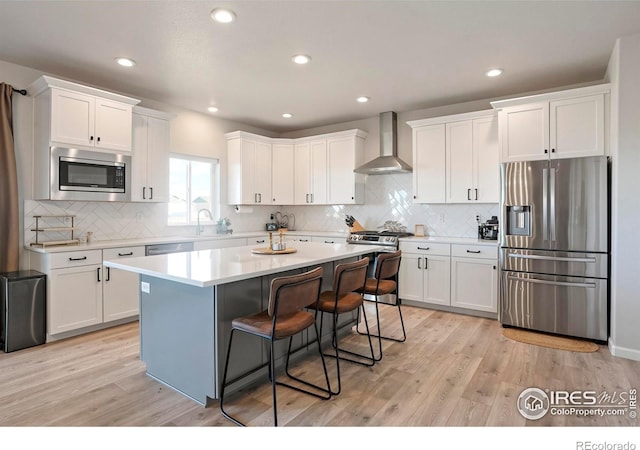 kitchen featuring white cabinets, wall chimney exhaust hood, and stainless steel appliances