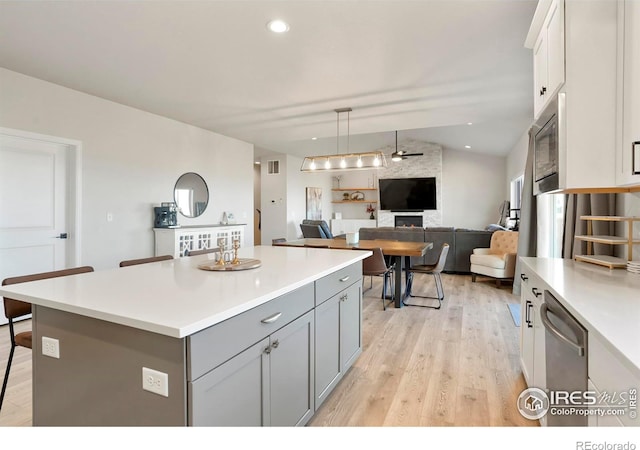 kitchen with open floor plan, a center island, vaulted ceiling, gray cabinets, and light countertops