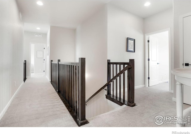 hall featuring recessed lighting, carpet floors, visible vents, baseboards, and an upstairs landing