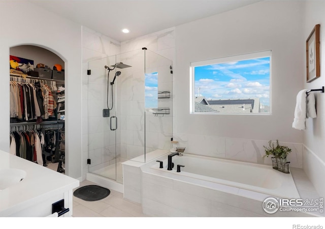 full bath featuring a garden tub, a walk in closet, vanity, a shower stall, and recessed lighting