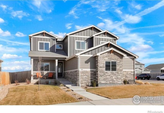 craftsman-style home with board and batten siding, fence, and a front lawn