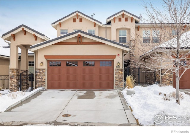 view of front facade with a garage, a tile roof, concrete driveway, stone siding, and stucco siding