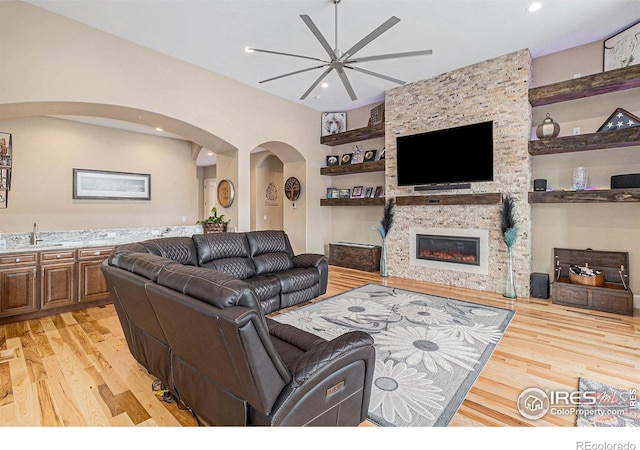 living area featuring built in features, recessed lighting, a fireplace, and light wood finished floors