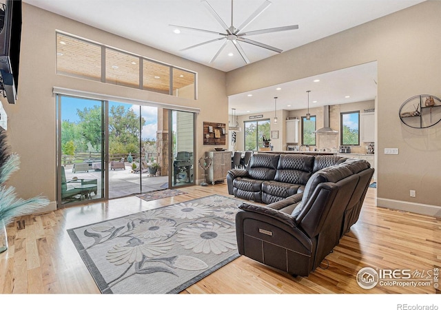 living room with light wood finished floors, recessed lighting, a high ceiling, and baseboards