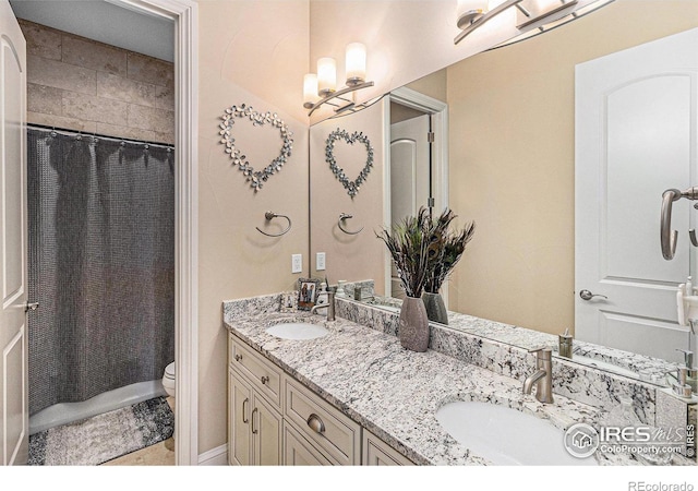 full bath with a sink, toilet, and double vanity