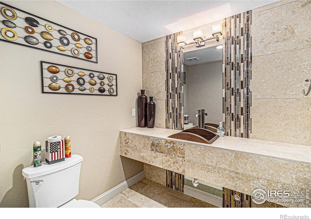 bathroom with toilet, baseboards, and a sink