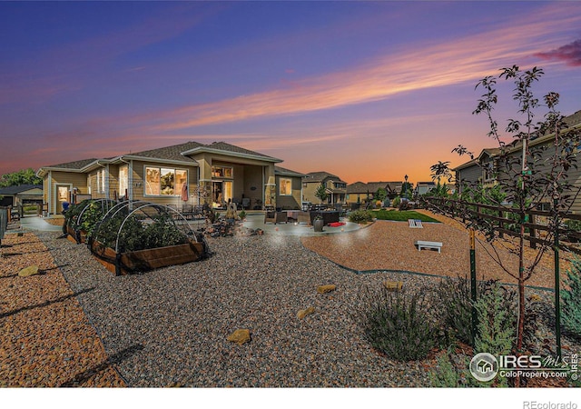 back of house at dusk featuring a patio area