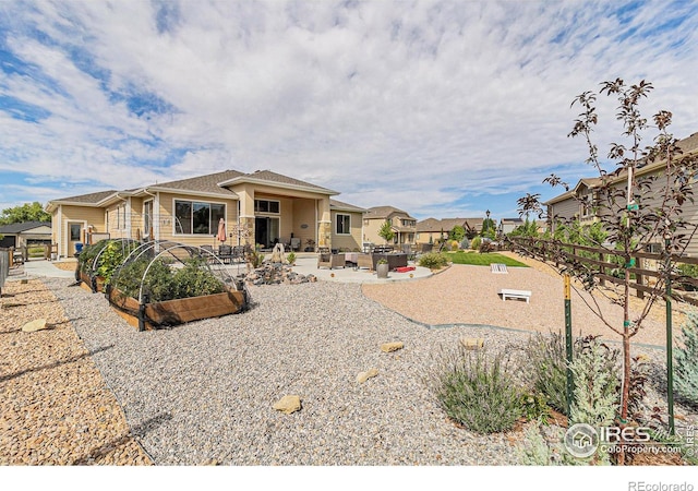 view of front of home featuring a garden, a residential view, fence, and a patio