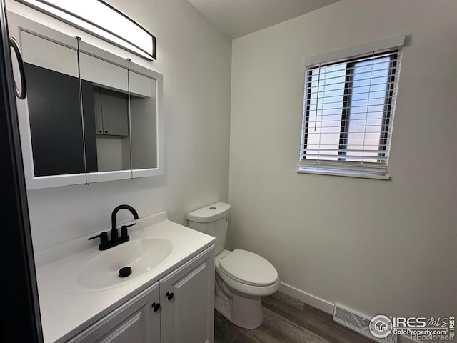 bathroom with visible vents, toilet, vanity, wood finished floors, and baseboards