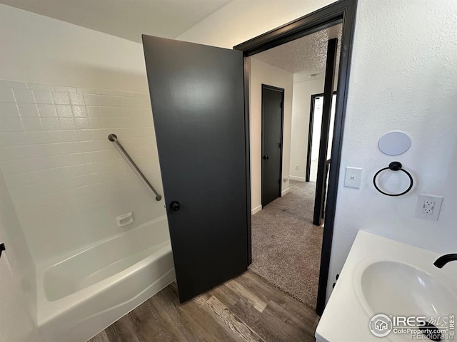 bathroom with a textured ceiling, tub / shower combination, wood finished floors, and vanity